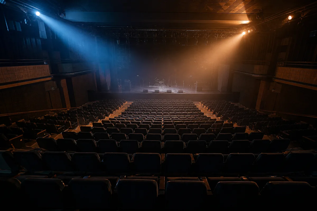 Salle de concert vide vue depuis les gradins sous une lumière rasante bleue et ambre